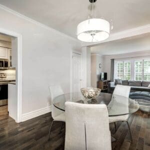 A dining room with white chairs and glass table.